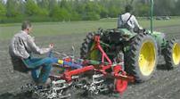 une personne a l'arriere du tracteur guide manuellement la bineuse