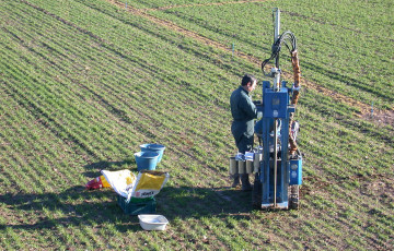 Un homme prélève un échantillon de terre parmi des plantes de céréales à paille en janvier 2026 en Limousin