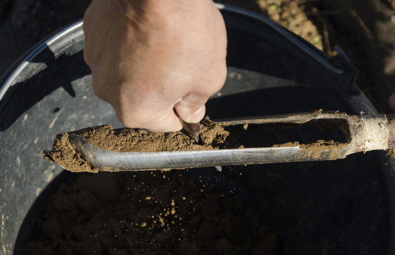 Prélèvement de terre : des mains vident la gouge de la tarière dans le seau début 2026 en Bretagne
